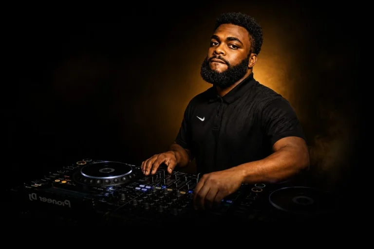 DJ Sabs performing behind the decks under warm stage lighting
