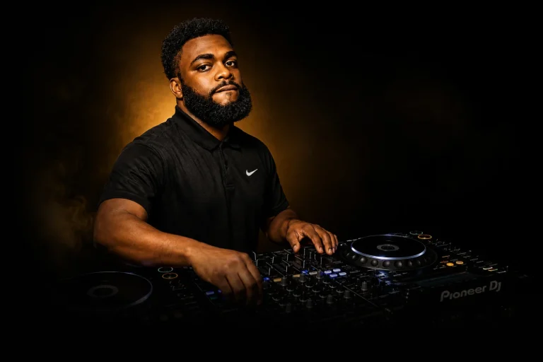 DJ Sabs performing behind the decks under warm stage lighting